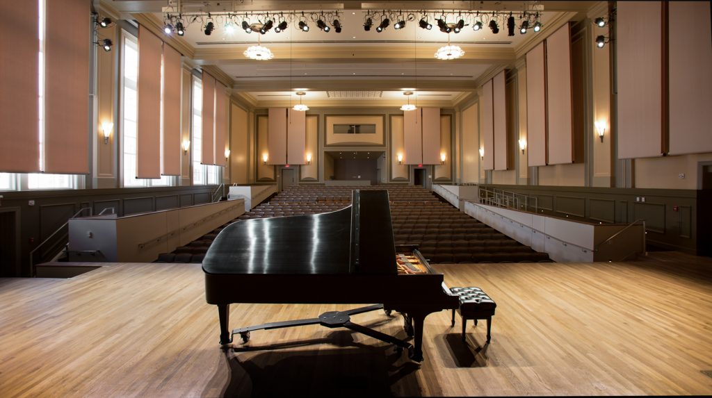 Grand piano with lid open on Moeser Auditorium stage, looking out into the hall.