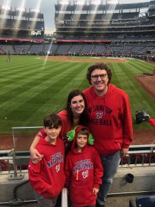 Max with his wife and two boys pose beside the field in the Washington Nationals baseball stadium.