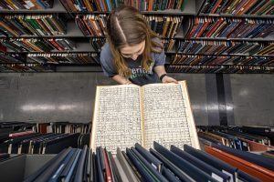 Student examines an open score amidst the music library stacks