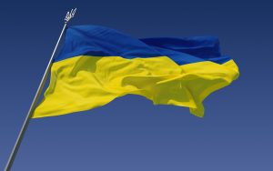 The Ukranian flag blows in the wind with blue sky in the background.
