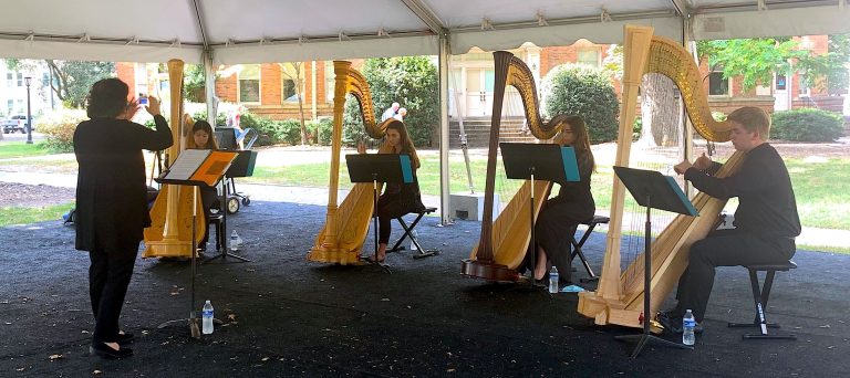 Director Laura Byrne leads 4 student harp players in an outdoor performance