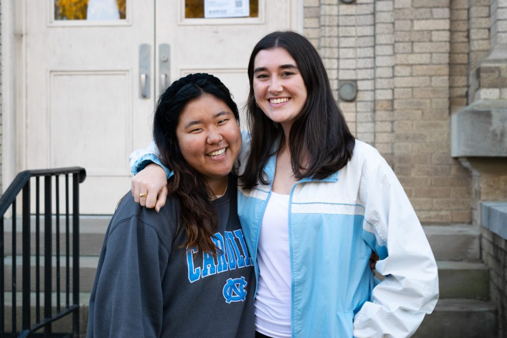 Nuria Shin and Casey Mentch stand together, smiling, outside Hill Hall.