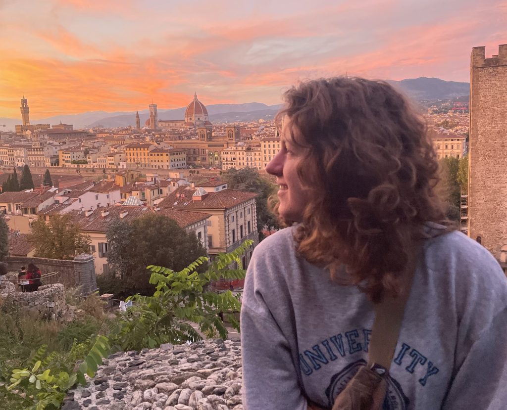 Madi Marks in front of a scenic overlook in Florence, Italy at sunset.