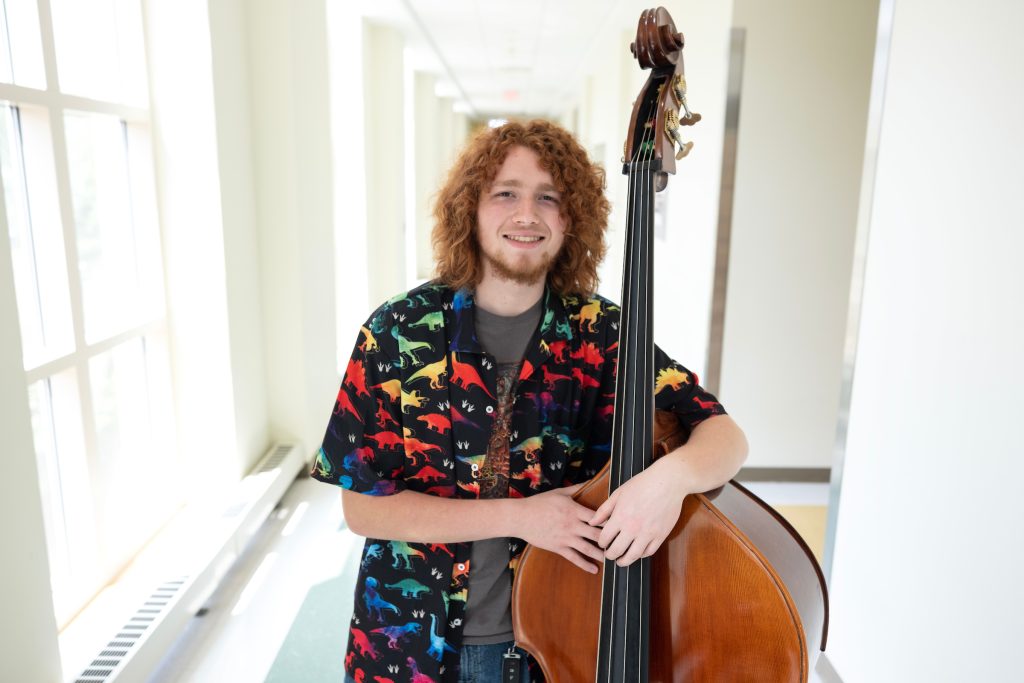 Sam Bivona stands with his upright bass in a hallway of Kenan Music Building.