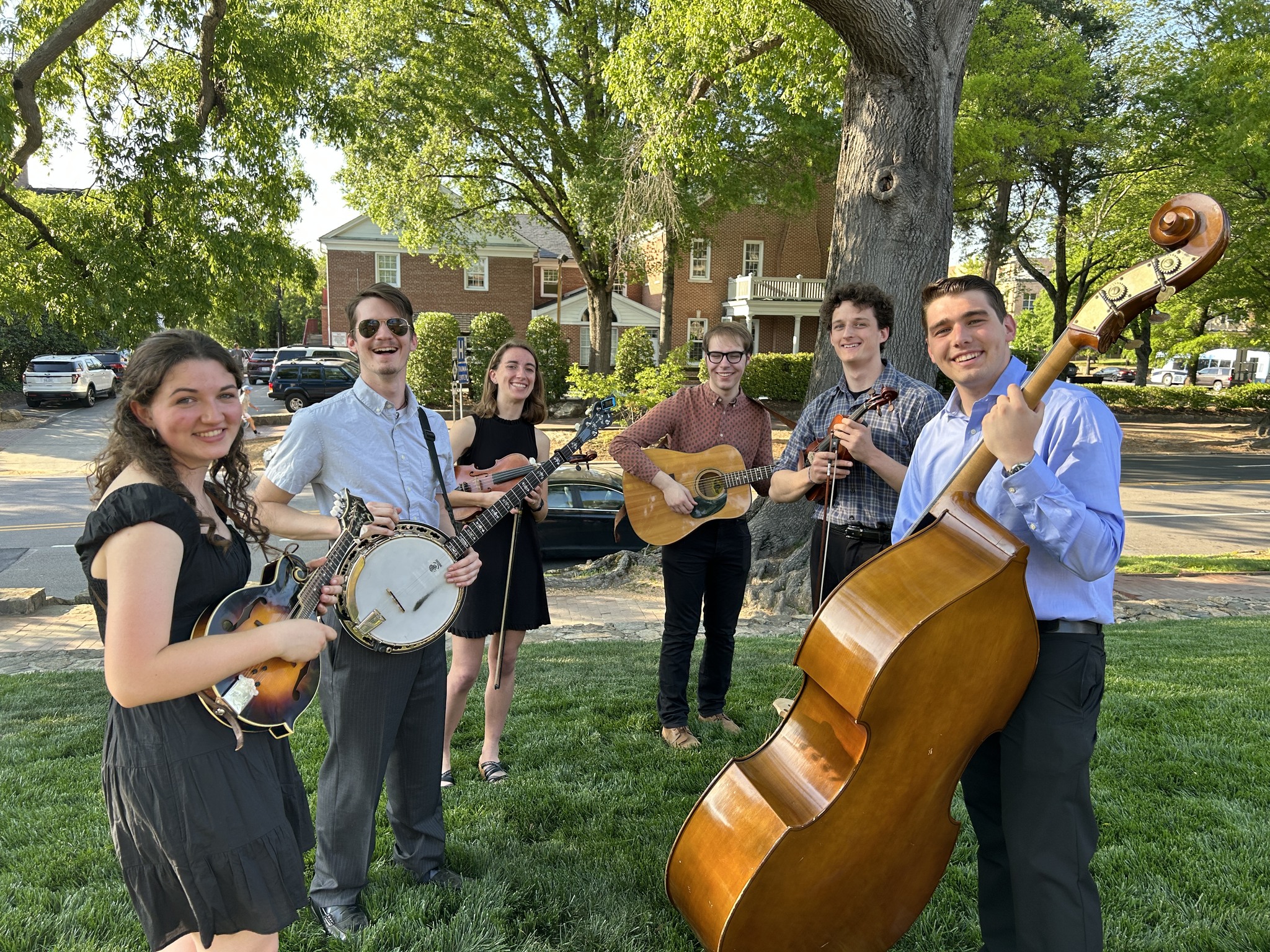 Carolina Bluegrass Band members stand smiling as they pause their rehearsal on the lawn of the Carolina Inn.