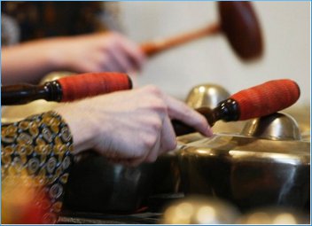 Close up of a student's hands holding mallets and playing the gamelan.
